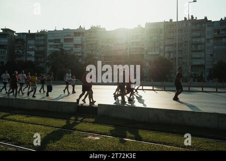 Izmir, Türkei, 10. September 2023: Läufer werden während des Izmir-Marathons zu Silhouetten gegen das helle Sonnenlicht auf dem Asphalt Stockfoto