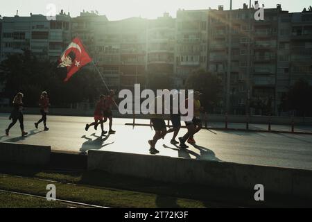 Izmir, Türkei, 10. September 2023: Läufer werden während des Izmir-Marathons zu Silhouetten gegen das helle Sonnenlicht auf dem Asphalt Stockfoto