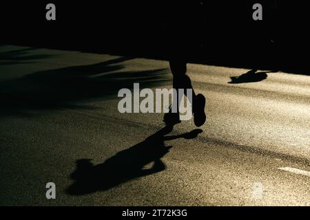 Izmir, Türkei, 10. September 2023: Läufer werden während des Izmir-Marathons zu Silhouetten gegen das helle Sonnenlicht auf dem Asphalt Stockfoto