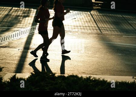 Izmir, Türkei, 10. September 2023: Läufer werden während des Izmir-Marathons zu Silhouetten gegen das helle Sonnenlicht auf dem Asphalt Stockfoto