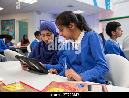 Asiatische Schüler, die einen Tablet-Computer im Unterricht an einer britischen Schule verwenden. Stockfoto