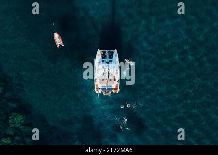 Fantastischer Blick von oben auf den Katamaran, der im Sommer im blauen Meer verankert ist. Reisehintergrund. Kreuzfahrturlaub. Stockfoto