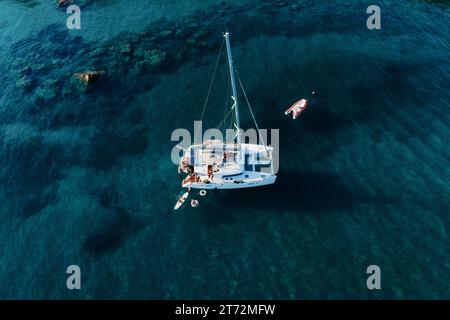 Fantastischer Blick von oben auf den Katamaran, der im Sommer im blauen Meer verankert ist. Reisehintergrund. Kreuzfahrturlaub. Stockfoto
