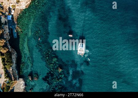 Fantastischer Blick von oben auf den Katamaran, der im blauen Meer verankert ist. Reisehintergrund. Stockfoto