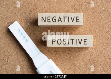 Negative und positive Wörter auf Holzblock mit Schwangerschaftstestkit. Stockfoto