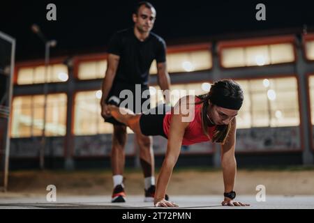 Gesunde Paare trainieren zusammen draußen im Park in der Nacht. Stockfoto
