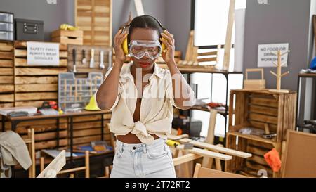 afroamerikanerin, die eine Sicherheitsbrille und Kopfhörer in der Zimmerei trägt Stockfoto
