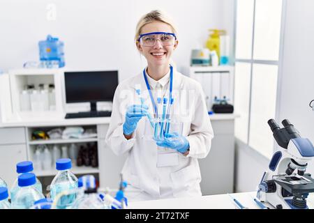 Junge blonde Wissenschaftlerin, die Reagenzgläser im Labor analysiert Stockfoto