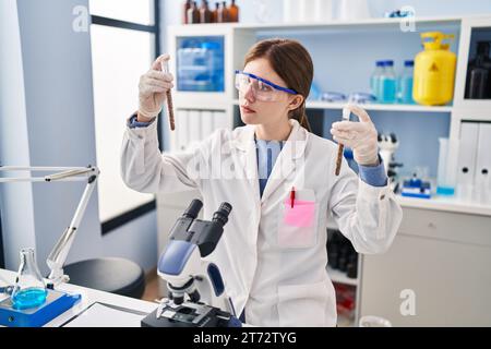 Junge blonde Wissenschaftlerin, die Reagenzgläser im Labor analysiert Stockfoto