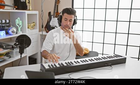 Attraktiver junger hispanischer Mann, ein talentierter Musiker, der sich in die Melodie eintaucht, leidenschaftlich das akustische Klavier spielt, in einem Kopfhörern in A l Stockfoto
