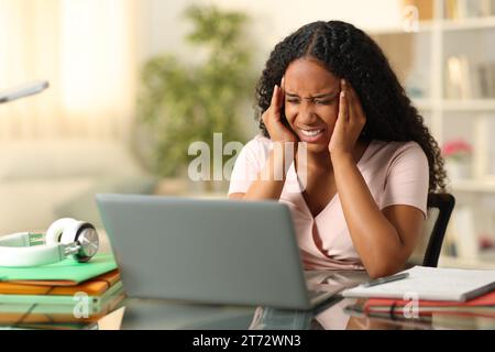 Schwarzer Student leidet an Migräne, der zu Hause mit einem Laptop studiert Stockfoto