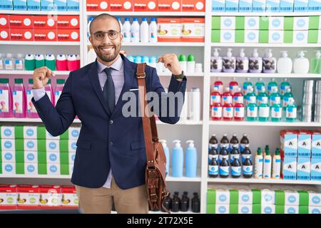 Hispanischer Mann mit Bart, der als Verkäufer in der Apotheke arbeitet, selbstbewusst mit einem Lächeln im Gesicht, mit stolzen und glücklichen Fingern auf sich zeigt. Stockfoto