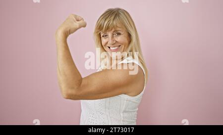 Schöne blonde Frau mittleren Alters, die vor Zuversicht und Freude strahlt, beugt ihren starken Arm über einen isolierten rosa Hintergrund. glücksbringer zum Ausdruck bringen, spor Stockfoto