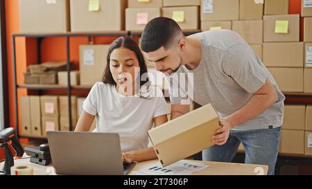 Mann und Frau arbeiten zusammen, zwei Büroangestellte lesen Paketinformationen auf Laptop im Lager Stockfoto
