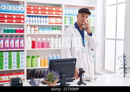 Junger hispanischer Apotheker, der in der Apotheke telefoniert Stockfoto