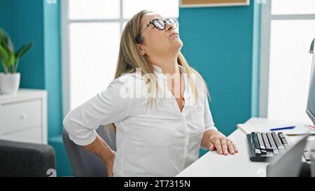 Mittelalter hispanische Geschäftsfrau leidet an Rückenschmerzen, die im Büro arbeitet Stockfoto