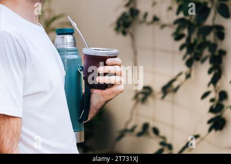 Ein Mann mit Thermos und Kürbis. Yerba Mate, traditionelles südamerikanisches Heißgetränk. Mittelalter lateinamerikanischer Mann draußen. Stockfoto