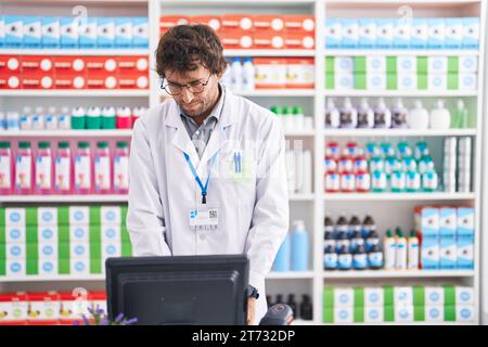 Junger hispanischer Apotheker mit Computer in der Apotheke Stockfoto
