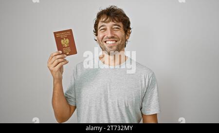 Ein glücklicher junger Mann, der vor Freude strahlt, hält stolz seinen polnischen Pass vor einem isolierten weißen Hintergrund fest Stockfoto