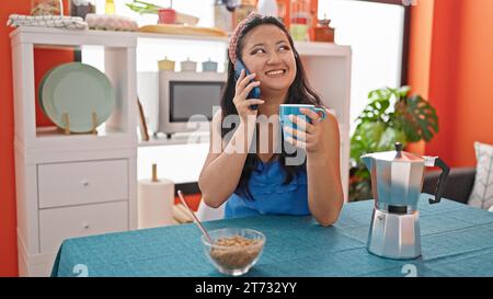 Junge chinesin beim Frühstück, die sich im Speisesaal mit dem Smartphone unterhielt Stockfoto