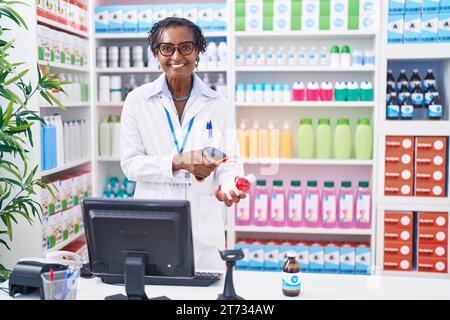 afroamerikanerin mittleren Alters, apotheke, die Pillen scannt, in der Apotheke Stockfoto