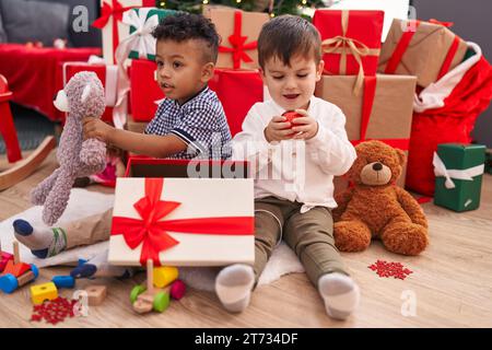 Süße Jungs, die weihnachten feiern und zu Hause ein Geschenk auspacken Stockfoto