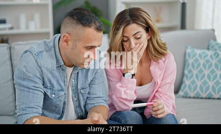 Mann und Frau Paar, die einen Schwangerschaftstest halten, schauen zu Hause verärgert aus Stockfoto