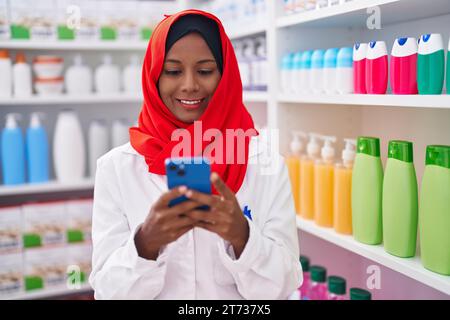 Junge, schöne Apothekerin mit Smartphone, die in der Apotheke arbeitet Stockfoto