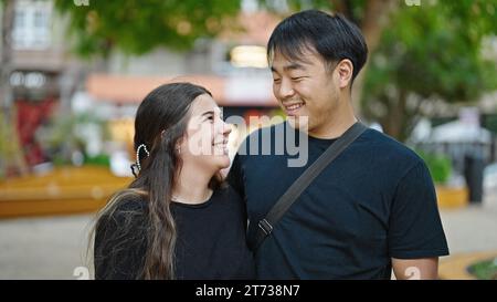 Mann und Frau Paar lächeln selbstbewusst und umarmen sich im Park Stockfoto