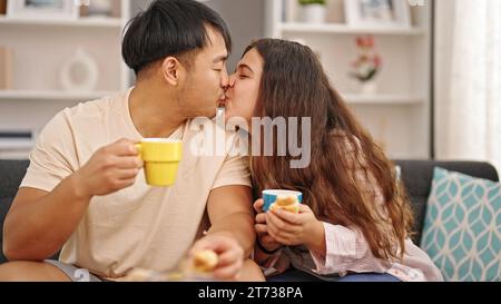 Mann und Frau sitzen auf dem Sofa und frühstücken zu Hause Stockfoto