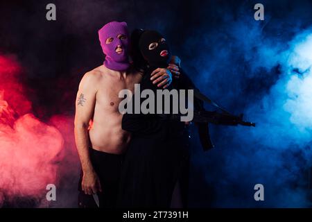 Ein Mann und eine Frau, deren Gesichter in einem dunklen Raum auf schwarzem Hintergrund bedeckt sind Stockfoto
