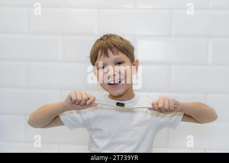 Süßer 8-jähriger Junge, der Bambuszahnbürsten hält und in die Kamera schaut Stockfoto