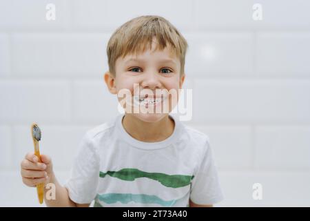 Süßer 5-jähriger Junge, der im Badezimmer Zähne mit Bambuszahnbürste putzt. Bild mit selektivem Fokus Stockfoto