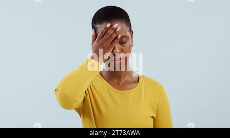 Frustrierte schwarze Frau, Kopfschmerzen und Stress aus Versehen, Ausfall oder Verlust vor grauem Studiohintergrund. Das Gesicht einer müden afrikanischen Frau oder eines Models Stockfoto