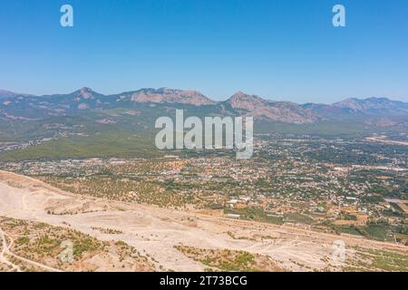 Ausgetrocknete Flussbett in einer ländlichen Landschaft mit den Bergen mit einer kleinen Siedlungsstadt an der Küste. Majestätische Landschaft mit Felsenstraße und Hügel Stockfoto