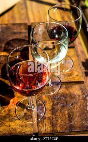 Drei Gläser mit drei verschiedenen Weinen auf einem Holztisch. Stockfoto