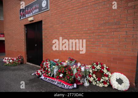 Manchester, Großbritannien. 13. November 2023. Sir Bobby Charlton's Leichenwagen passiert den Old Trafford Football Ground, wo Blumen und Nachrichten an der Gedenkstätte für die Münchner Katastrophe von 1958 hinterlassen wurden. Der Leichenwagen ging an der Trinity Statue vorbei und ging über den Sir Matt Busby Way zum Begräbnis im Stadtzentrum von Manchester. Bild: Garyroberts/worldwidefeatures.com Credit: GaryRobertsphotography/Alamy Live News Stockfoto