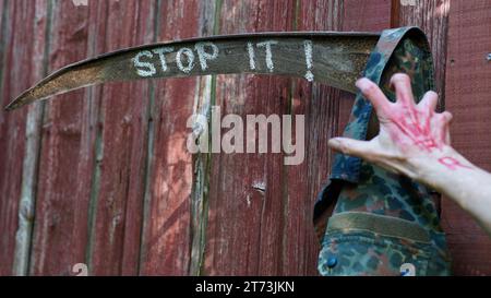 Rosty Sense, HÖR AUF, ES drauf zu schreiben. Eine Hand mit KRIEG in Rot, die an einer Militärjacke greift. Stockfoto