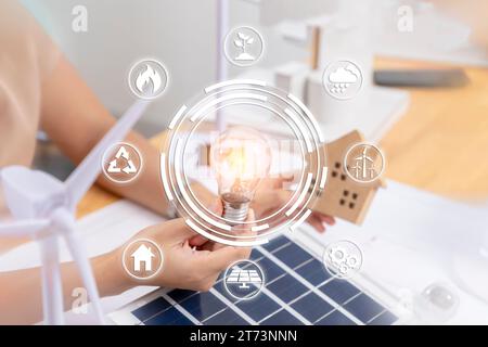 Junger asiatischer Architekt mit Windmühlen, der ein Modell für erneuerbare Windhäuser entwirft. Und Sonnenlicht Stockfoto