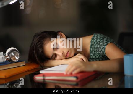 Müder überarbeiteter Student, der nachts zu Hause über Notizen schläft Stockfoto