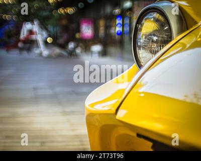 Nahaufnahme des alten gelben Oldtimer-Wagens, Frontlicht über dem öffentlichen Raum mit Bokeh-Licht Stockfoto