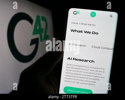 Person, die ein Mobiltelefon mit Webseite des Emirati Technology Company Group 42 Holding Ltd. Hält (G42) mit Logo. Konzentrieren Sie sich auf die Mitte des Telefondisplays. Stockfoto