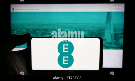 Person, die ein Smartphone mit dem Logo des britischen Telekommunikationsunternehmens EE Limited vor der Website hält. Schwerpunkt auf dem Display des Telefons. Stockfoto