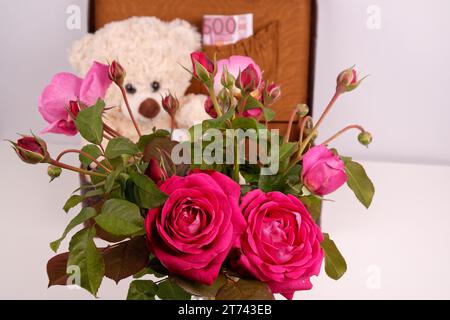 Ein Strauß aus verschiedenen roten Rosen mit grünen Blättern in einer Vase, Nahaufnahme Stockfoto