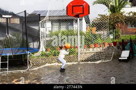 Mädchen, das sich bereit macht, zu springen und den Ball in den Korb zu tauchen, vertikales Foto Stockfoto