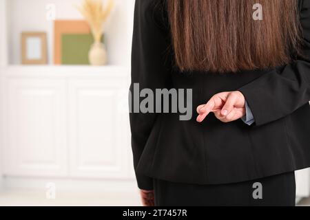 Frau, die die Finger hinter ihrem Rücken zuhause kreuzt, Nahaufnahme. Leerzeichen für Text Stockfoto