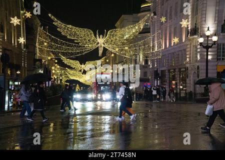 UK Weather, London, 12. November 2023: Die Weihnachtslichter der riesigen Engel auf der Lower Regent Street spiegeln sich in einer regnerischen Nacht am Picadilly Circus im West End auf nassen Straßen. Anna Watson/Alamy Live News Stockfoto