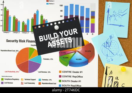 Geschäftskonzept. Es gibt Geschäftsdiagramme, Haftnotizen und schwarzes Papier mit der Aufschrift auf der Tafel – Build Your Assets Stockfoto