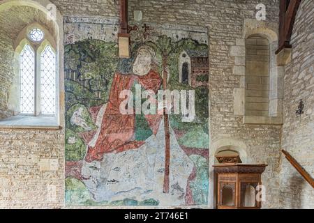 Wandgemälde von St. Christopher aus dem 14. Jahrhundert in der Kirche St. Mary Magdalene aus dem 12. Jahrhundert im Cotswold-Dorf Baunton, Gloucestershire, Großbritannien Stockfoto