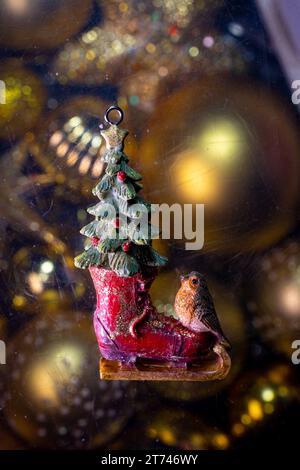 Weihnachtsspielzeugskulptur für einen Weihnachtsbaum auf dem Hintergrund goldener Kugeln. Stockfoto